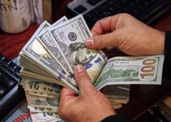 A money changer counts U.S. dollar banknotes at a currency exchange office in Ankara – Colorado Springs Gazette