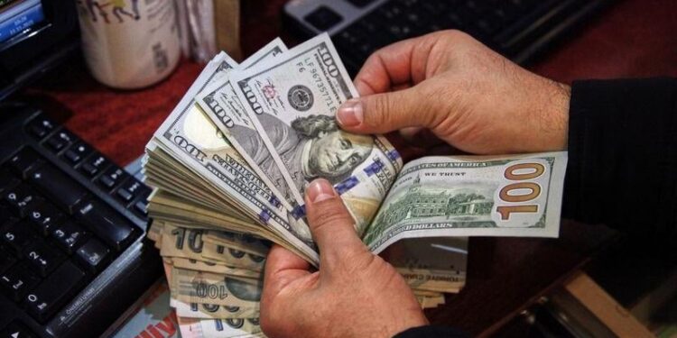 A money changer counts U.S. dollar banknotes at a currency exchange office in Ankara – Colorado Springs Gazette